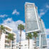 Modern skyscraper is being built, towering over traditional buildings with palm trees in Limassol, Cyprus